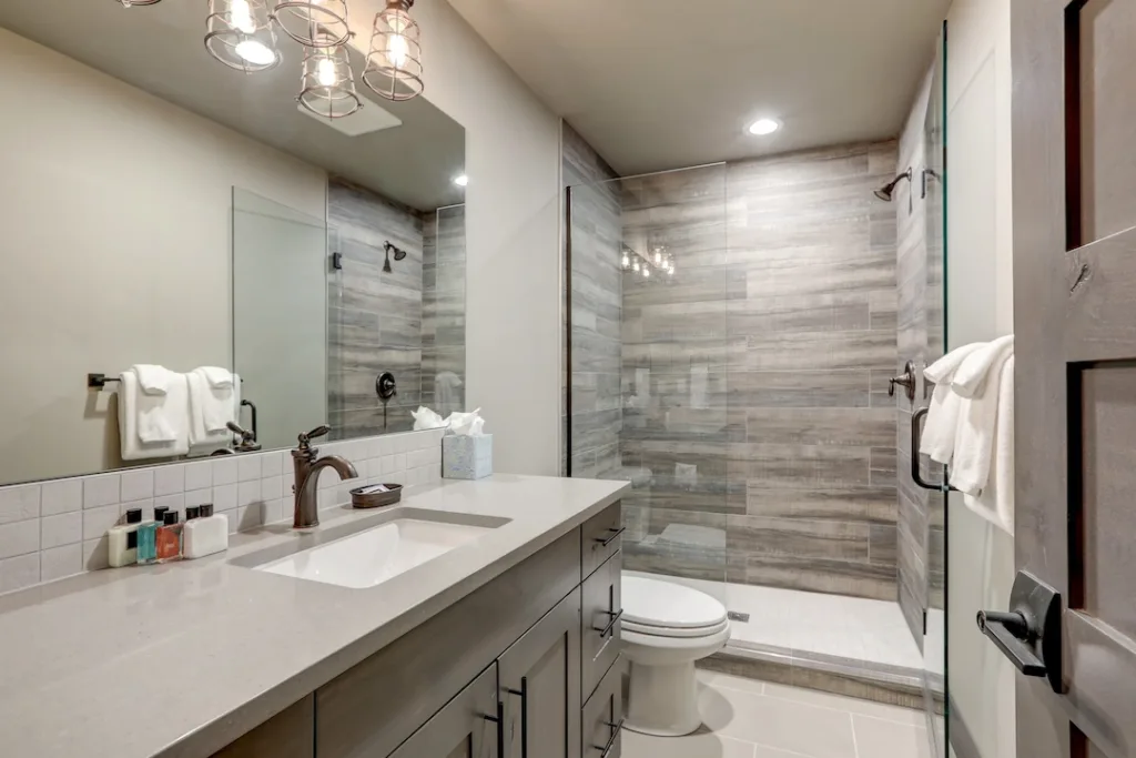 Natural new classic bathroom interior with new glass and ceramic tiles walk in shower and grey walls.