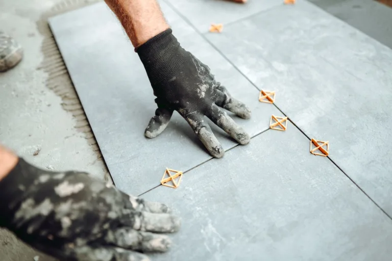 industrial worker, handyman installing big ceramic tiles on balcony floor. Balcony area covered in ceramic tiles with strong adhesive